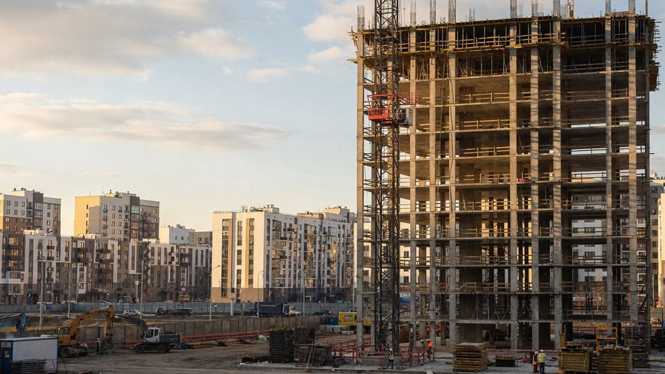 монолитный каркас жилой башни и башенный кран на фоне московского района